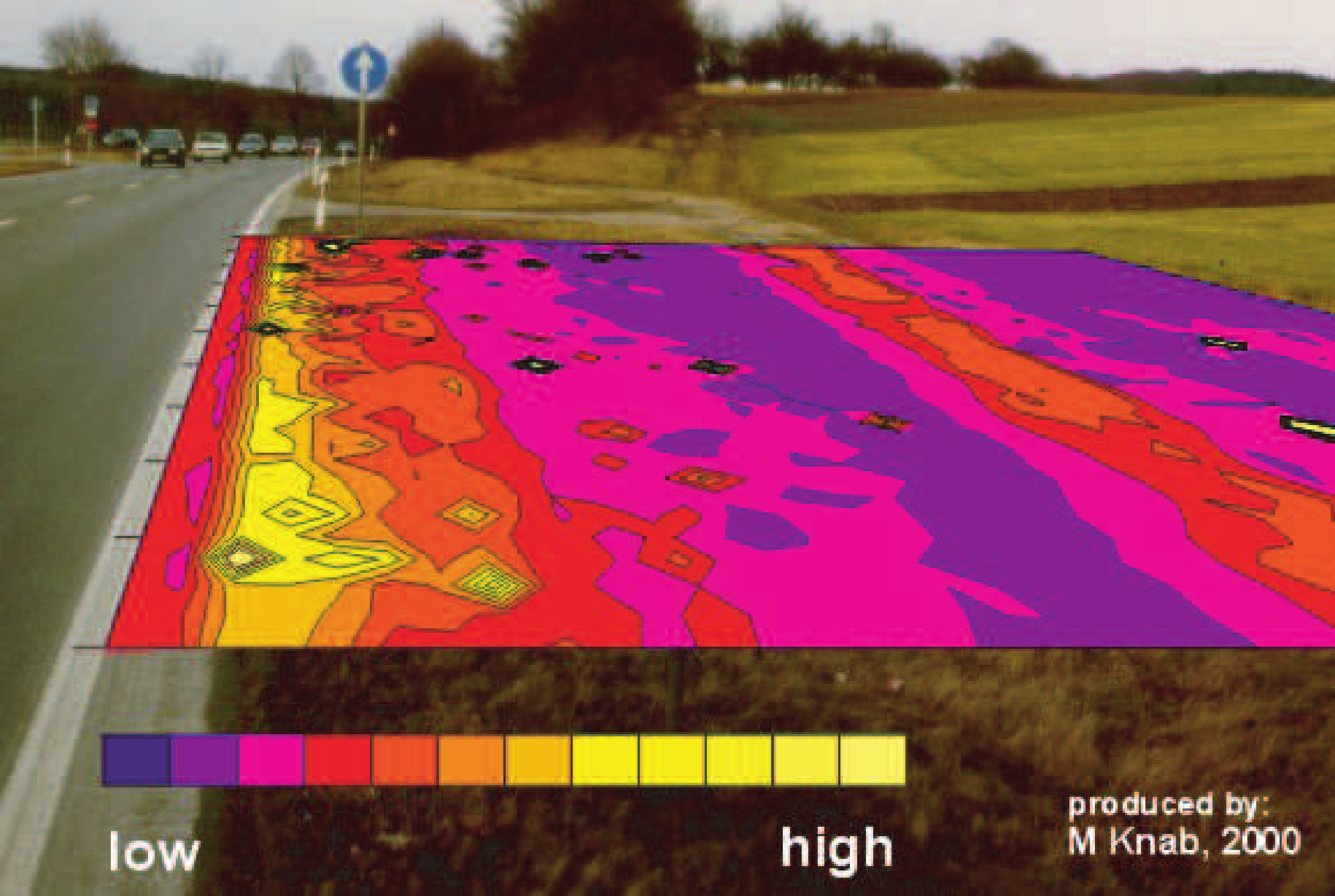 Color contour map of magnetic susceptibility overlaid on a roadside photograph, showing highest values (yellow) near the road and decreasing values (purple) with distance.